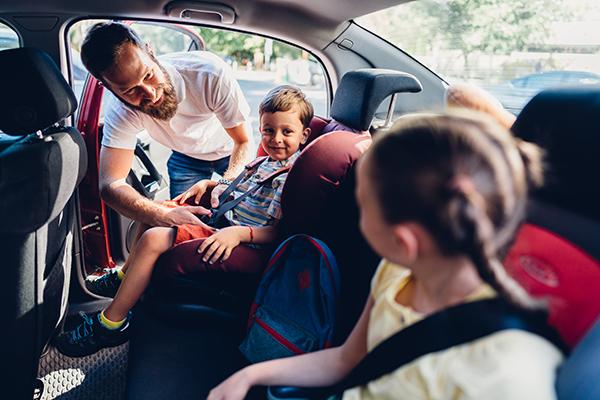 dad buckling kids into carseats
